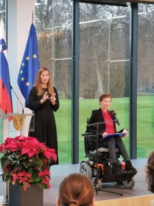 Na sliki je mag. Mateja Toman,, predsednica NSIOS. Ob njej tolmačka slovenskega znakovnega jezika
